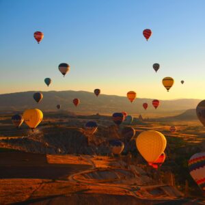 Vibrant hot air balloons soar over Cappadocia's breathtaking landscape at sunrise, creating a magical scene.